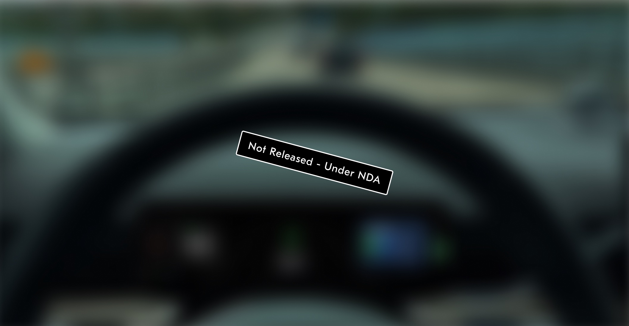 Blurred view over the steering wheel toward the road and driver display, with a Not Released, Under NDA stamp across it