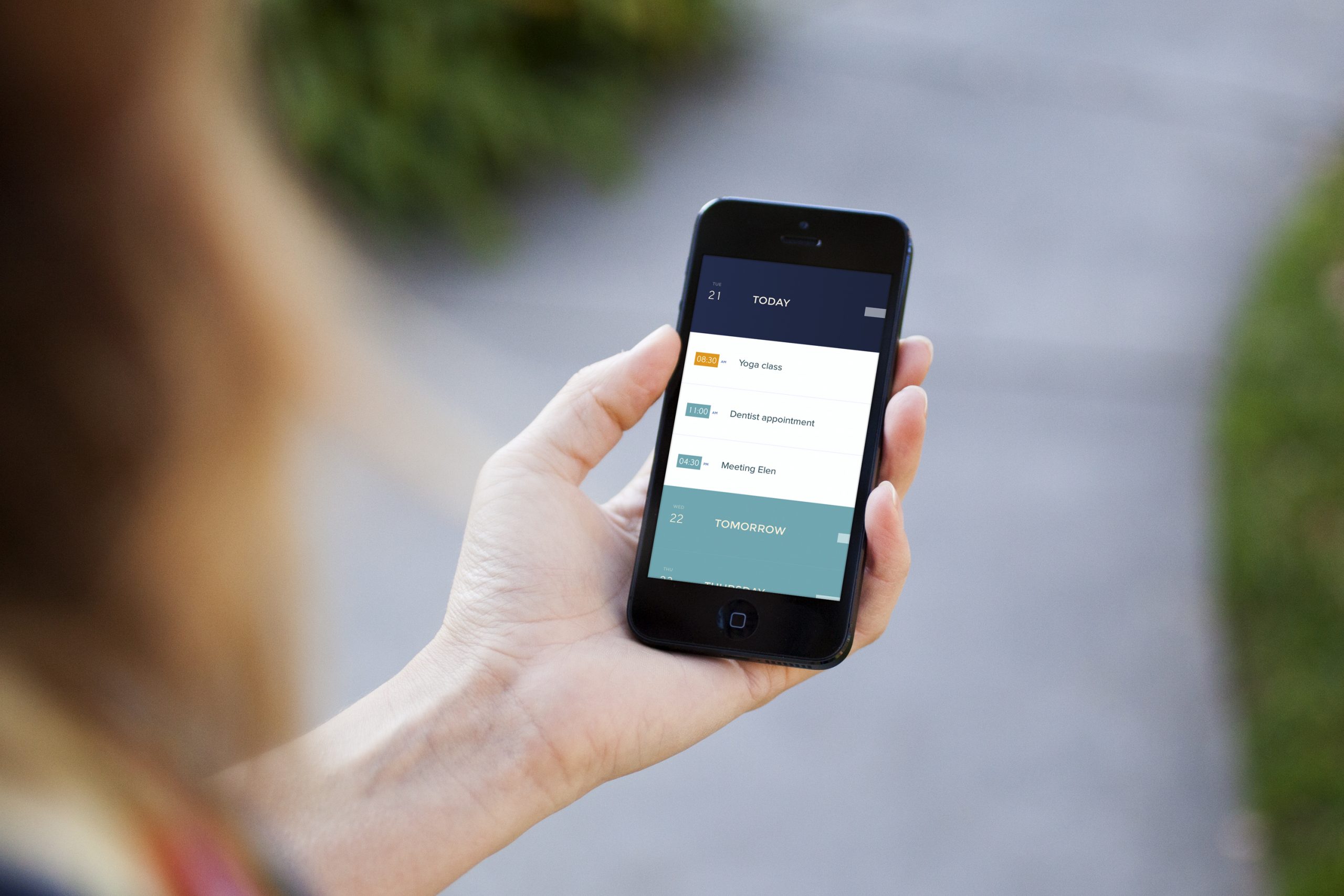 Person holding a phone showing the Peek Calendar list of appointments