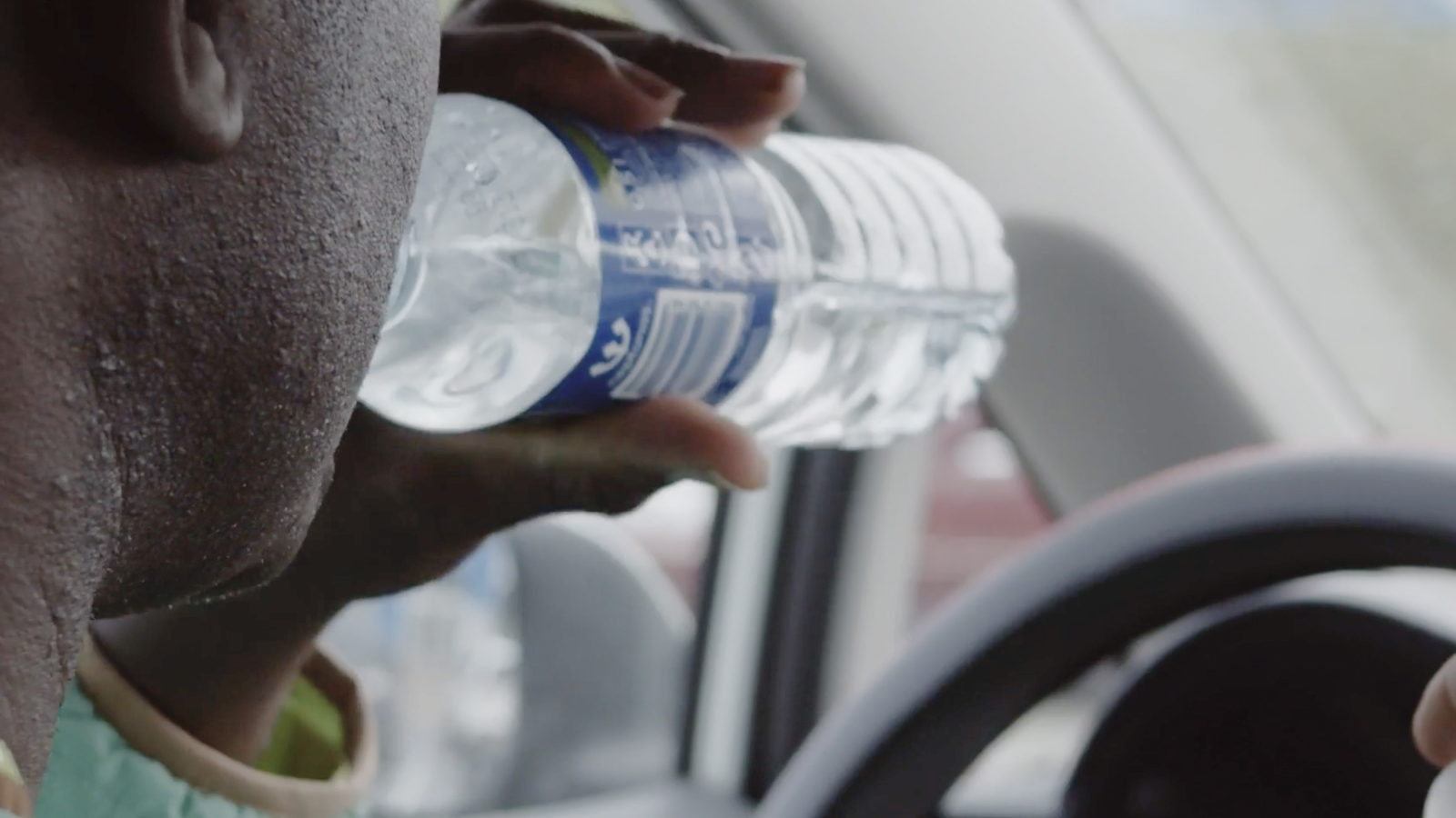 A man drinking water from a bottle while sitting in a car