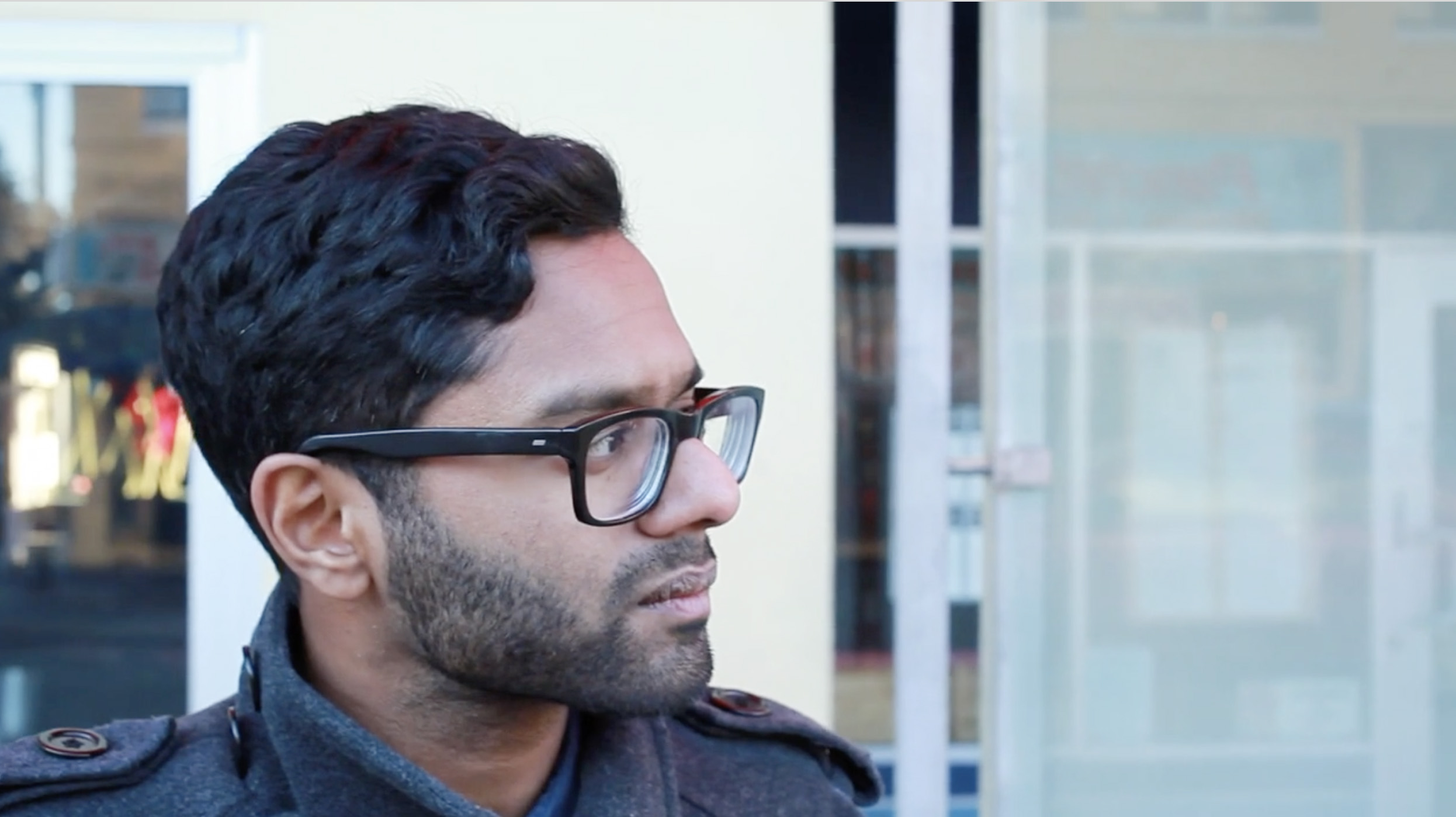 A man in glasses looking off to the side on a city street