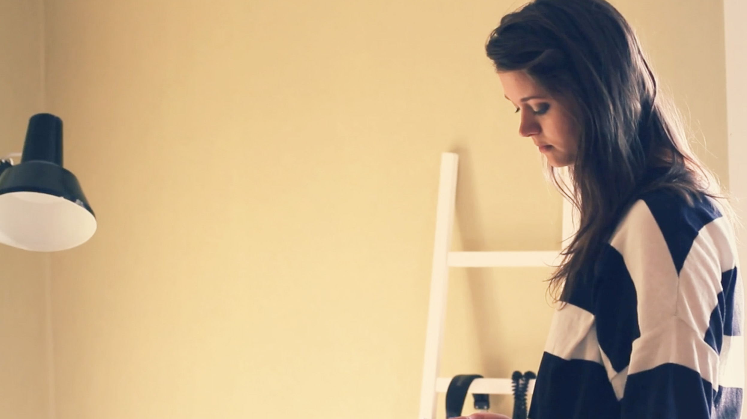 A woman in a striped sweater looking down at something in a softly lit room